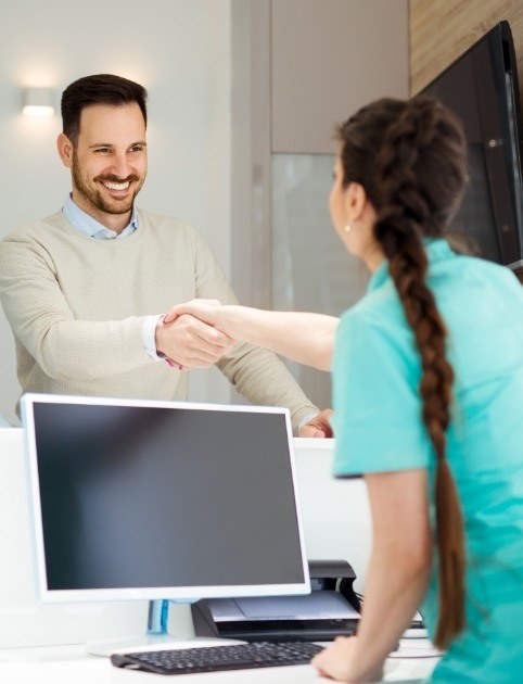 Man shaking hands with dental team member after reviewing dental insurance and financing options