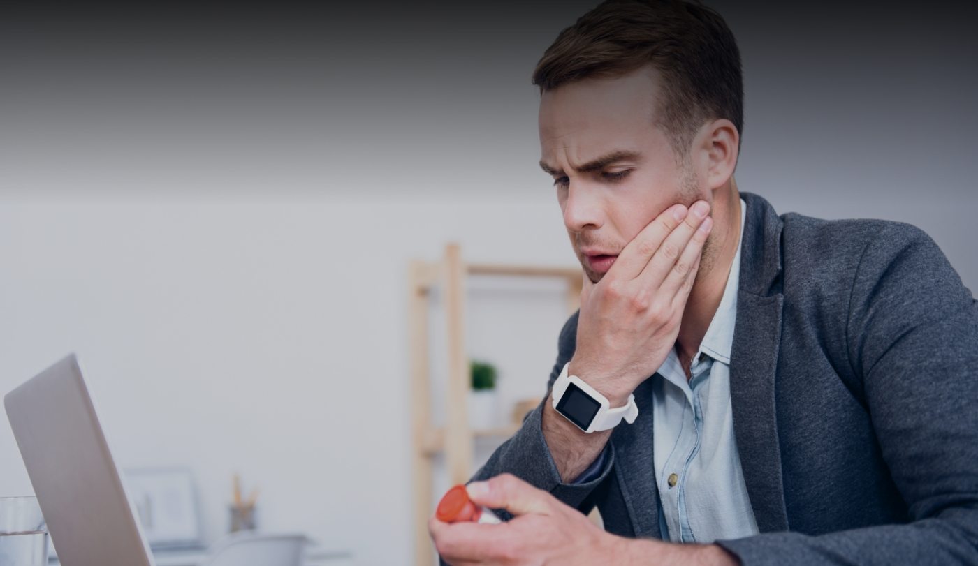 Man in need of T M J therapy holding jaw in pain