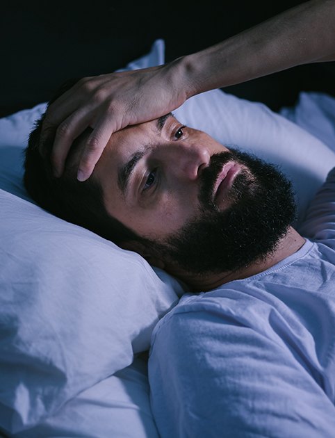 Bearded man lying awake in bed