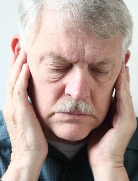 Man with ear pain holding his ears