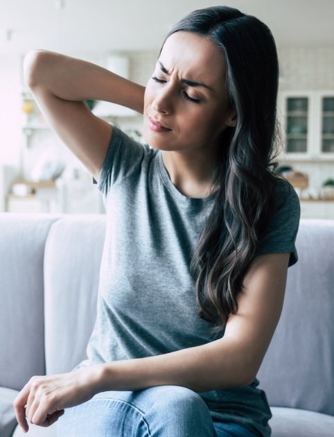 Woman with neck pain rubbing the back of her neck