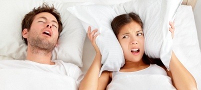 Woman frustrated next to snoring man who needs to take the sleep assessment