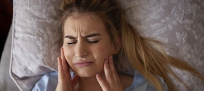 Woman in pain before T M J therapy holding her jaw