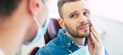 Man in pain talking to dentist during T M J consultation