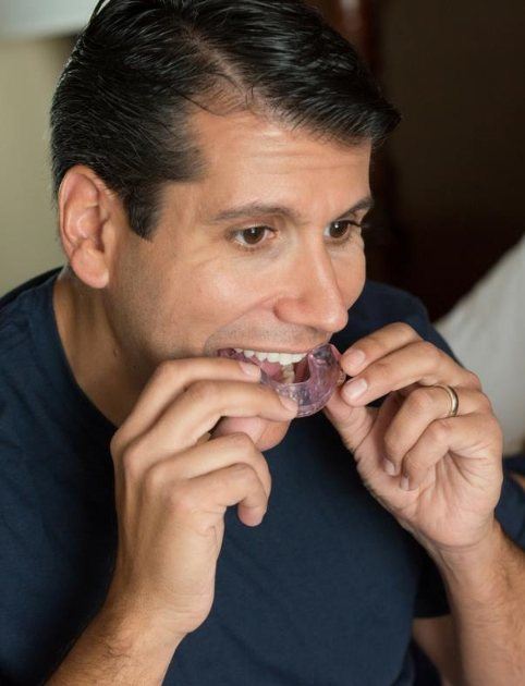 Man placing oral appliance to treat sleep apnea