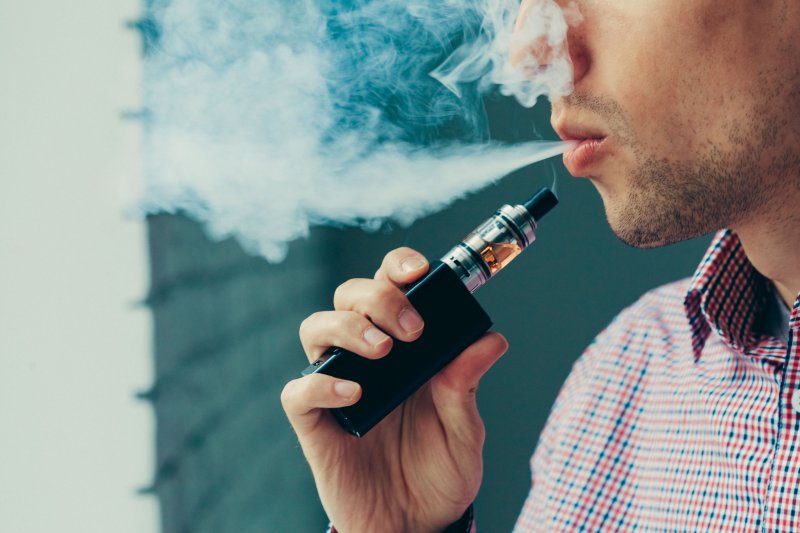 Bearded man vaping with electronic cigarette