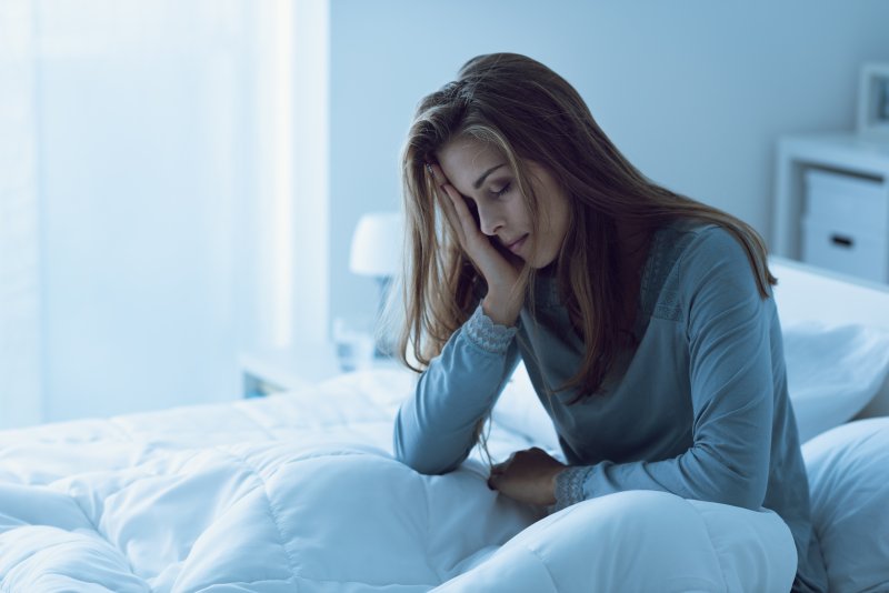 Distressed blond woman awake in bed rubbing temple