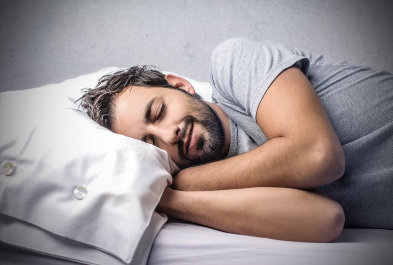 a man asleep on his side laying in bed