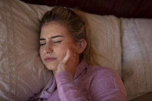 Woman with jaw pain laying in bed
