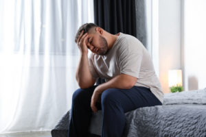 Depressed overweight man on bed at home