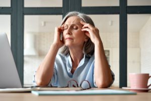 Woman sitting at desk, suffering migraine pain