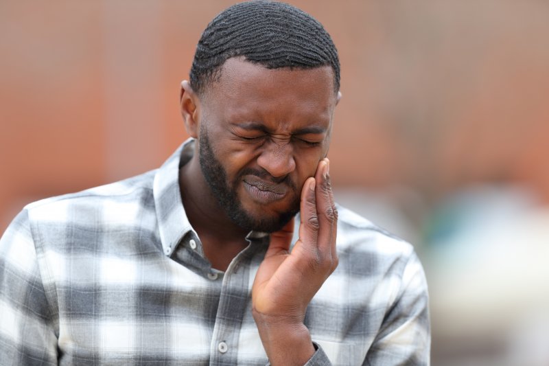 A man holding his jaw due to TMJ disorder pain