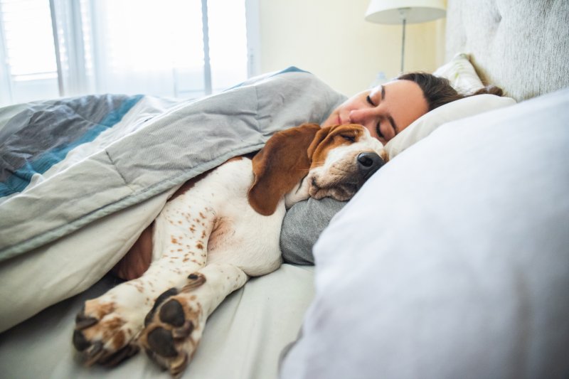 A woman sleeping alongside her pet dog