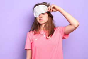 Woman sleepily lifting her sleep mask off her face